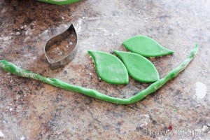Pumpkin Cake - Roll out some green fondant and make the leaves using a leaf cutter. Use the veining tool to create texture on the leaves. Roll green fondant to create the vines.