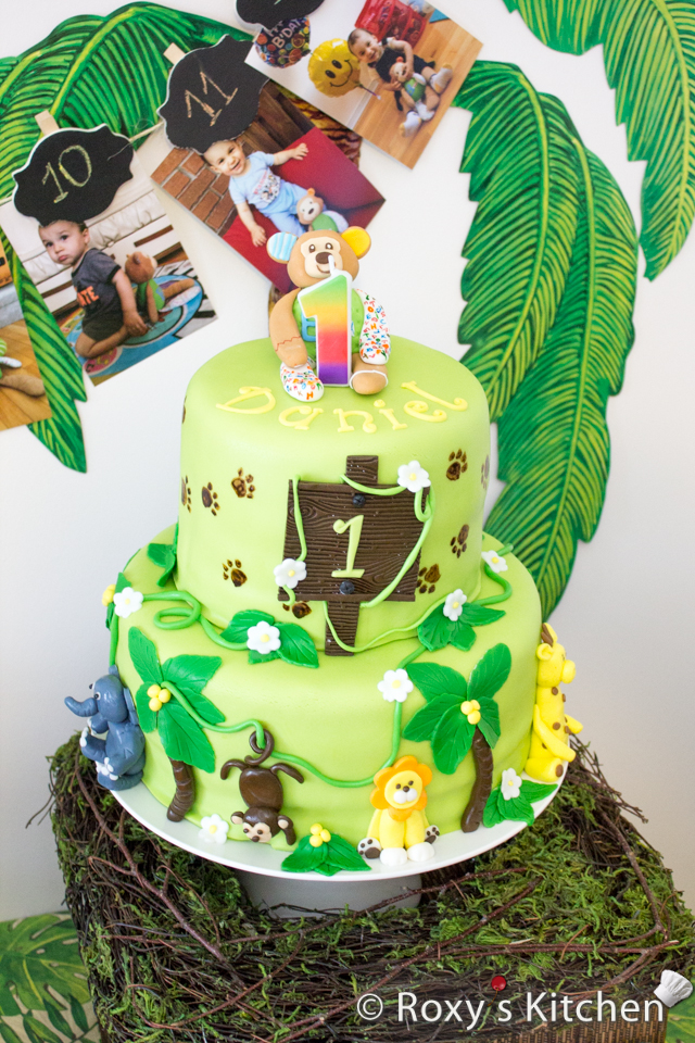 Safari / Jungle Themed First Birthday Party - Dessert Ideas: Two-tier Jungle Animals Birthday Cake. It's a chocolate & walnut cake covered in fondant and decorated with fondant leaves and animals - lion, monkey, giraffe, elephant