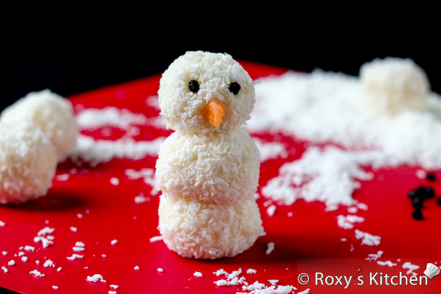 Homemade Raffaello Snowmen - Use a toothpick to apply a small amount of candy coating to the wild blueberries and attach them to the snowman’s face.  Cut out a nose shape out of an orange fuzzy peach gummy and attach it using white candy coating as glue.