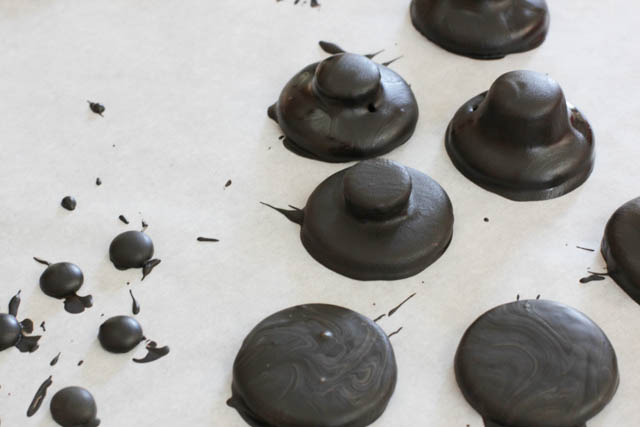 Then place the hat on a fork and carefully dip each it into the melted chocolate. Tap the fork a bit on the side of the bowl so that the excess chocolate drips off. Cover three more Oreo halves with chocolate in a similar way.