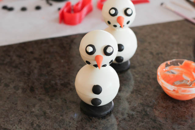 Assembling the chocolate snowmen -Attach the nose using a bit of orange melted chocolate. 