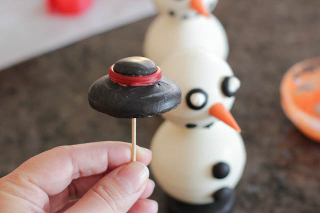 Assembling the chocolate snowmen -Make a tiny hole in the bottom of the hat using a toothpick.
