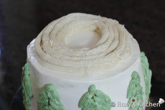 To make the Christmas wreath, place the hummus in a piping bag and pipe a round circle on top of the cake. 