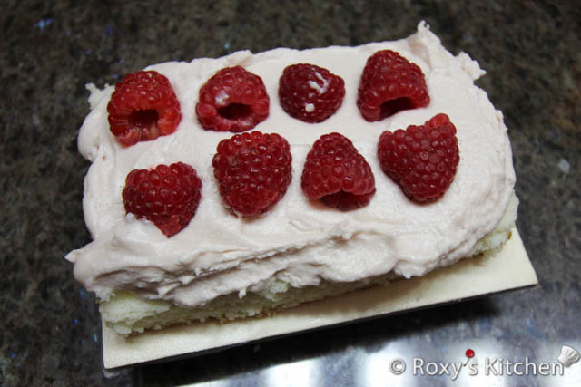 Moisten it with sugar syrup and spread raspberry cream cheese buttercream filling on top.  Add a layer of fresh raspberries and place the second cake layer on top. 