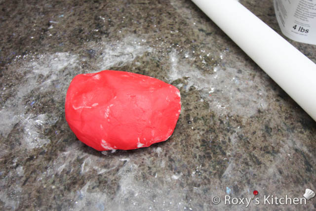 Dust your working surface with some powdered sugar or cornstarch. Knead the red fondant until it has a workable consistency and it doesn’t feel and look dry. 