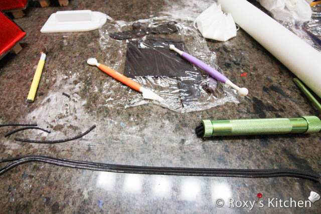 Use a clay/fondant extruder, fitted with the round disc, to make thin ropes out of black fondant. 
