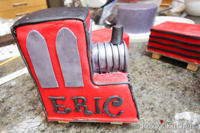 Use the Upper Case & Number Tappit Cutters to make the letters of your kid's name (e.g. ERIC) and age (1) out of black fondant.