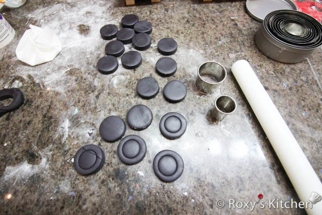 Roll out black fondant about 6 mm (1/4’’) thick to make the wheels. Cut circles using the 3.2 cm (1.25’’) circle cutter. Then use the smaller 2.5 cm (1’’) circle cutter to mark a circle on each wheel as seen in the picture. 