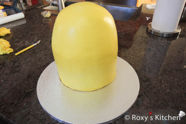 Gently lift fondant over rolling pin and place it on the side of the cake. Start unrolling the fondant from the side of the cake and across the top to the other side.