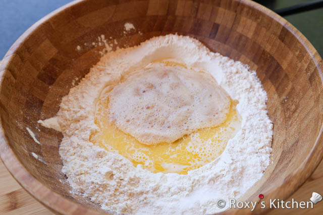 Create a well in the center of the dry ingredients and pour in the yeast mixture, melted butter, warm milk and 1 egg.