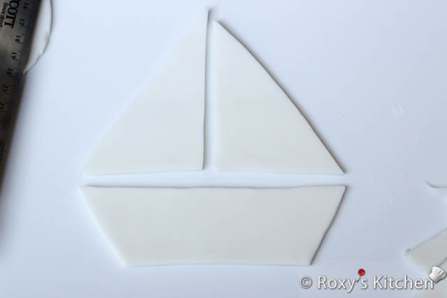 Roll out some red fondant about 1/4 cm (1/10’’) thick and cut out a slightly smaller triangle than your sails.