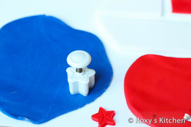 Roll out red and blue fondant about 1/4 cm (1/10’’) thick. Use a small star plunger and cutter to cut out three little stars.