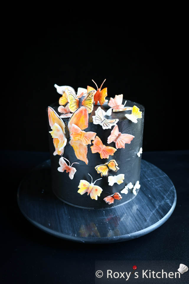 Creating an elegant Black Cake with Butterflies is an exquisite way to celebrate a special occasion. This 1-tier, elegant black cake is adorned with vibrant butterflies made out of fondant. It is a moist chocolate cake filled with whipped chocolate ganache with walnuts and frosted with Swiss meringue buttercream. 