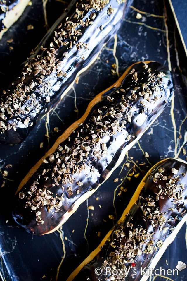 Eclairs topped with dark chocolate ganache and golden shredded chocolate 