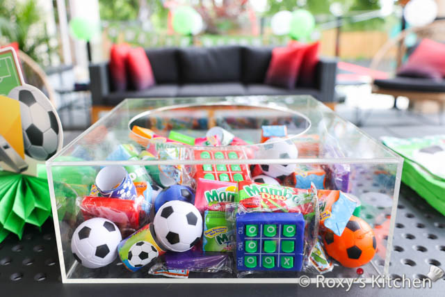 For our first party, I placed all the party favours in an acrylic cake stand. We had soccer-themed slap bracelets, squishy/foam soccer balls as well as tic-tac-toe keychains and some sweets. Kids picked what they liked after we cut the cake. 