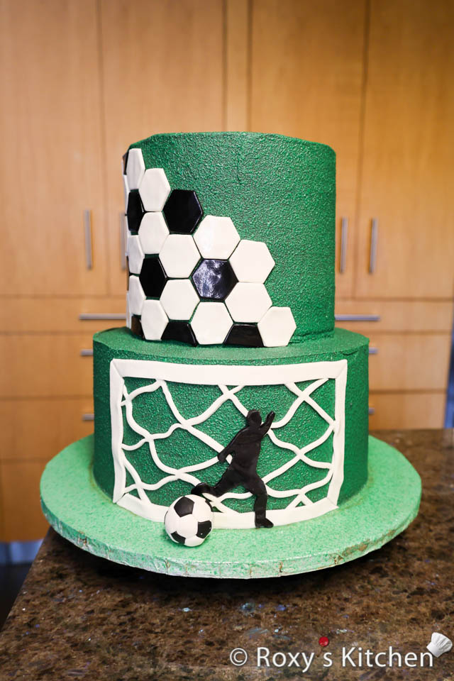 Brush a bit of water on the back of the fondant soccer player and attach it to the cake.