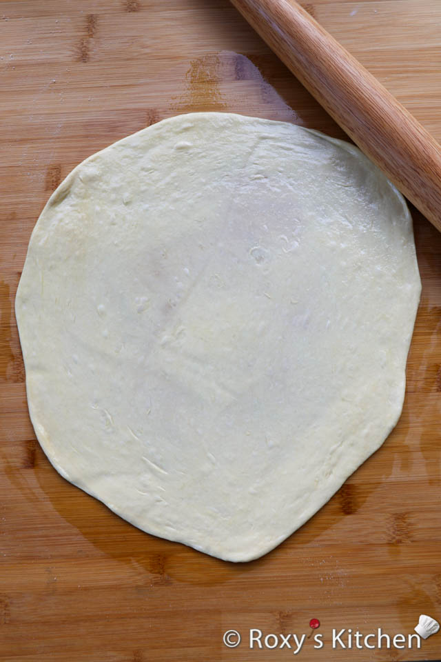 Spread a bit of vegetable oil on the piece of dough you’re working with. Then, begin pressing and stretching the dough a bit with your hands. You can also use a rolling pin to roll it out a bit. 