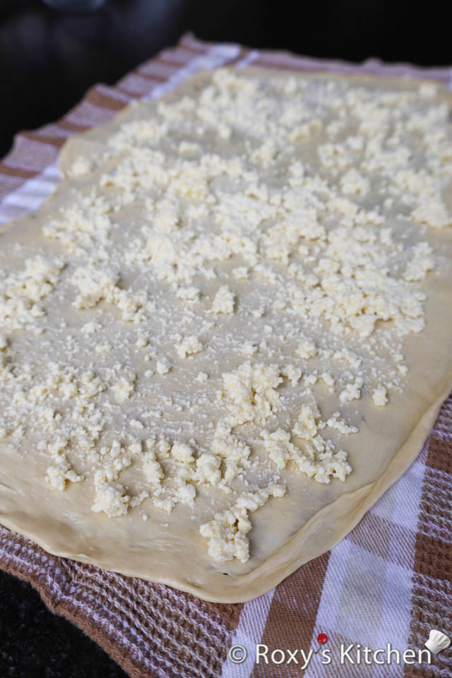 Once the dough is stretched thinly, spread a layer of the prepared cheese filling evenly over the surface.