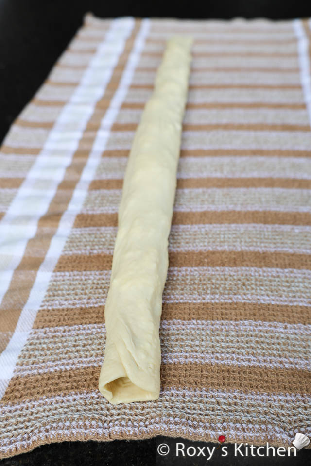 Using the kitchen towel, carefully roll the dough into a log enclosing the cheese filling within. 