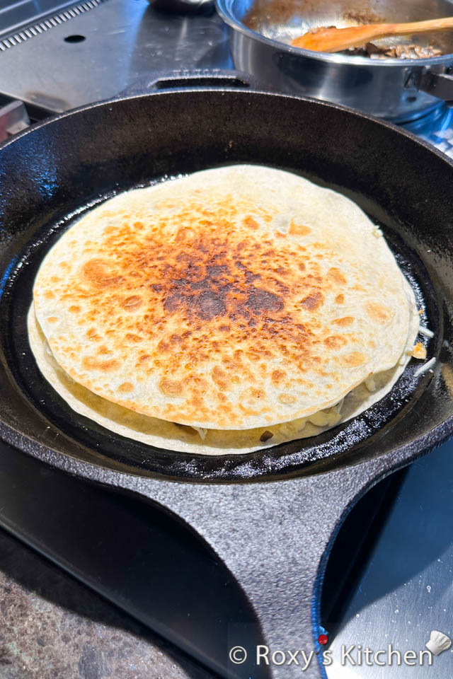 Cook the filled tortilla on medium heat until the bottom is golden brown. Flip it carefully and cook it on the other side. The cheese should be melted and the tortilla crispy. 
Remove the mushroom quesadilla from the pan, cut it into quarters and enjoy! 